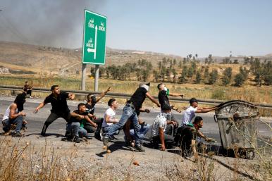 Palestinians throw stones near the West Bank border with Israel.