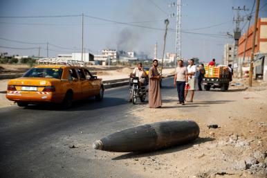 Palestinians view an unexploded Israeli shell in Gaza