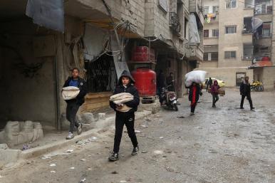 Boys carry bread as they walk along a street in Jaramana, on the outskirts of Damascus, Syria - source: Reuters