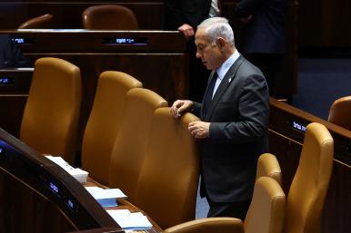 Photo of Israeli prime minister Binyamin Netanyahu standing alone in parliament.