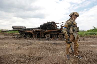 Ukrainian soldier beside destroyed Russian tank in Novodarivka, Ukraine