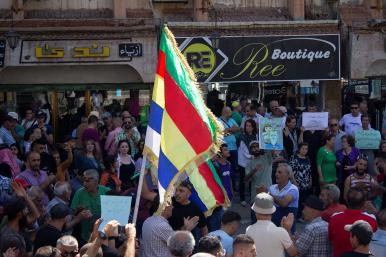 Protesting Syrians in the town of Suwayda hold signs and Druze flags - source: Reuters