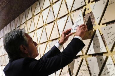 Secretary of State Antony Blinken places a tile that reads "Light in the darkness" on a wall at the Abrahamic Family House in Abu Dhabi, October 14, 2023.