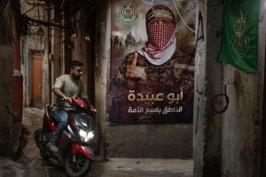 A man rides a scooter by a Hamas poster in a Palestinian refugee camp in Lebanon, May 18, 2024.