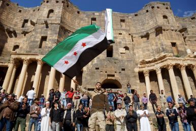 Protesters wave a Syrian opposition flag during a demonstration at a Roman ruin in Deraa Province in 2016 - source: Reuters