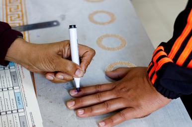 Photo of a Palestinian poll worker inking a voter's finger in Gaza.