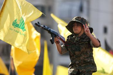 A child marches in a Hezbollah parade, holding a toy gun - source: Reuters