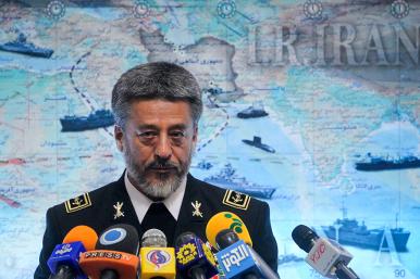 Iran's navy commander speaks in front of a map