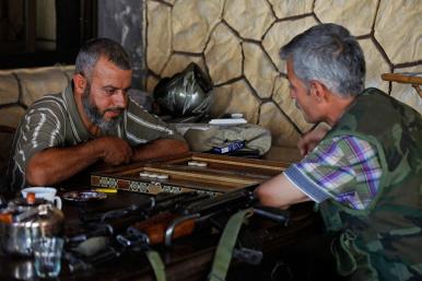 Syrian rebel fighters play a board game in a cafe