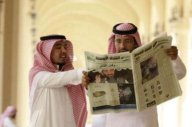 Saudi men read a newspaper - source: Reuters