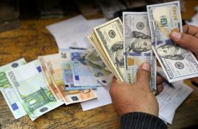 A money changer counts dollar and euro notes