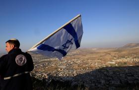 An Israeli settlement activist displays the Israeli flag near Nablus in the West Bank