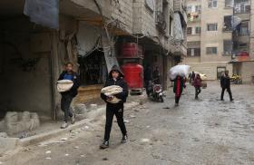 Boys carry bread as they walk along a street in Jaramana, on the outskirts of Damascus, Syria - source: Reuters