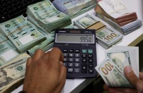 A Beirut money changer handles Lebanese pound and U.S. dollar notes - source: Reuters