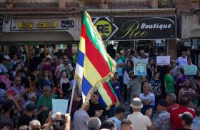 Protesting Syrians in the town of Suwayda hold signs and Druze flags - source: Reuters