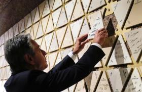 Secretary of State Antony Blinken places a tile that reads "Light in the darkness" on a wall at the Abrahamic Family House in Abu Dhabi, October 14, 2023.