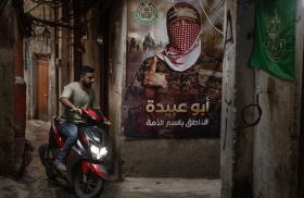 A man rides a scooter by a Hamas poster in a Palestinian refugee camp in Lebanon, May 18, 2024.