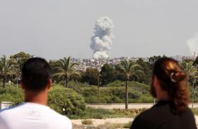 Men watch as smoke rises after an Israeli bombing of Hezbollah sites in southern Lebanon in September 2024 - source: Reuters