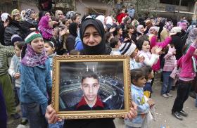 A Syrian woman holds a portrait of her missing son during a protest against the Assad regime in 2012 - source: Reuters