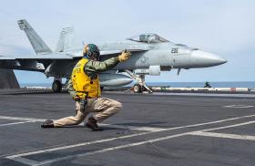 Photo of an F-18 fighter jet launching from a U.S. aircraft carrier.