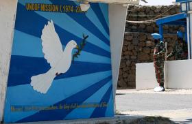 A UNDOF soldier on guard duty next to a mural of a dove of peace - source: Reuters
