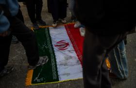Protesters trample on an Iranian flag - source: Reuters