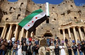 Protesters wave a Syrian opposition flag during a demonstration at a Roman ruin in Deraa Province in 2016 - source: Reuters