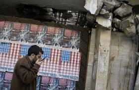 A man speaks on his phone in Beirut, Lebanon, in front of posters depicting the U.S. flag - source: Reuters
