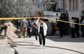 An Iranian woman walks by the scene of a U.S. airstrike in Tehran - source: Reuters