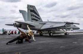 A crewman directs the landing of an F-18 on the USS Abraham Lincoln - source: Department of Defense