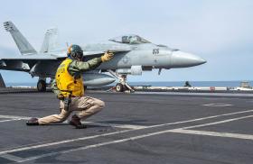 A sailor directs the launch of an F-18 from the flight deck of the carrier USS Harry S Truman - source: Department of Defense
