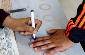 Photo of a Palestinian poll worker inking a voter's finger in Gaza.