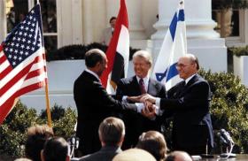 President Jimmy Carter, Egyptian President Anwar Sadat, and Israeli Prime Minister Menachem Begin shake hands at the White House as the Camp David Accords are announced.