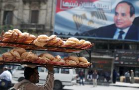 A bread seller in Cairo walks past a sign promoting President Sisi - source: Reuters