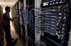 A man manipulates cables on a bank of internet data servers - source: Reuters