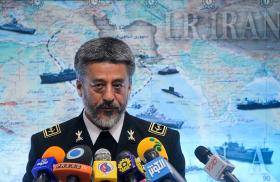 Iran's navy commander speaks in front of a map