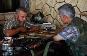 Syrian rebel fighters play a board game in a cafe